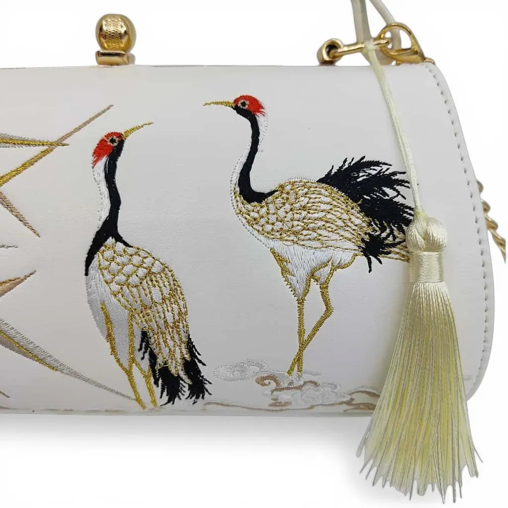 close‑up of red‑crowned crane embroidery and cream tassel detail on white chinese style handbag