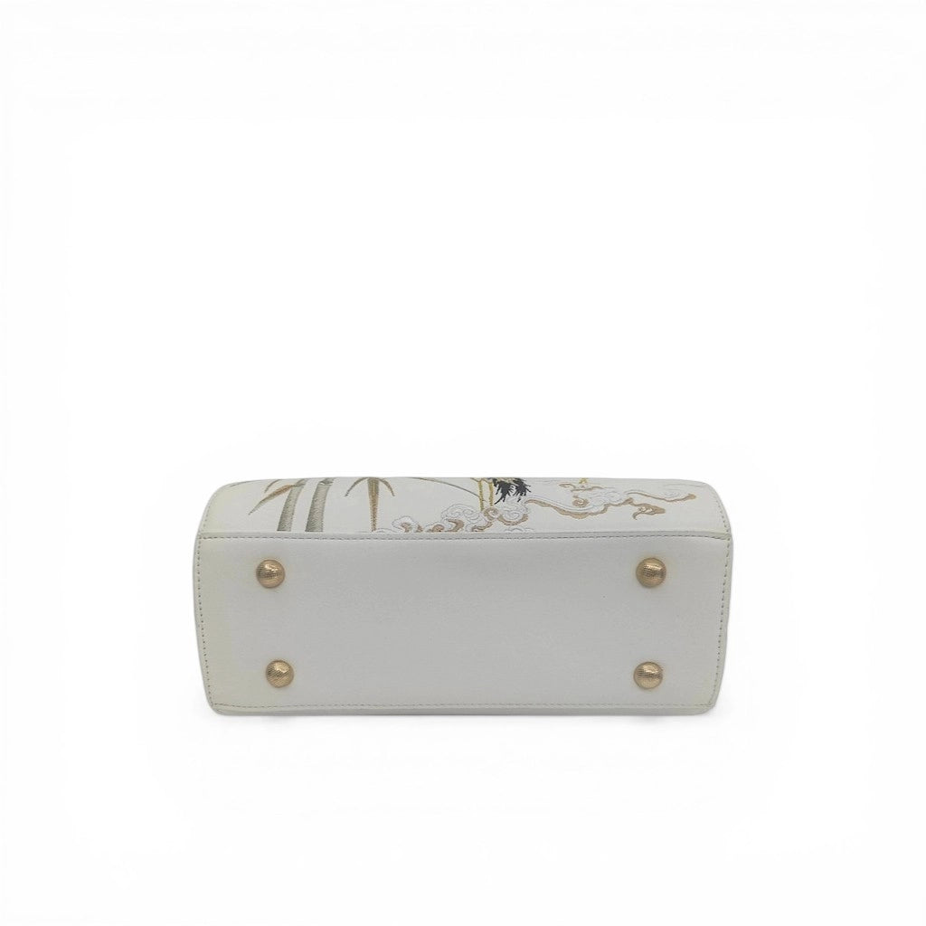 bottom detail of white crane embroidered handbag with golden metal studs and cloud pattern embroidery
