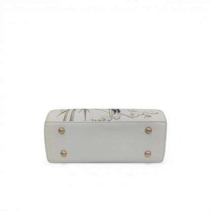 bottom detail of white crane embroidered handbag with golden metal studs and cloud pattern embroidery