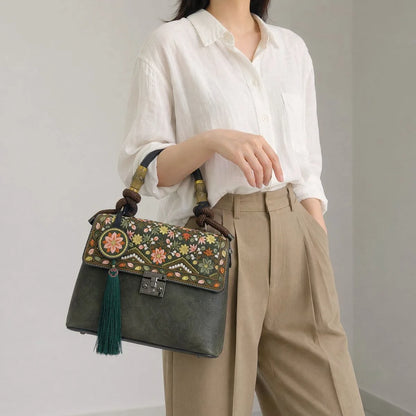 Faceless Asian woman carries dark green vintage handbag under arm, wearing white linen shirt and khaki trousers, plain light gray indoor workplace background
