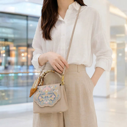 Fashionable woman wearing white linen shirt and khaki wide leg trousers, crossbody beige embroidered handbag in modern shopping mall