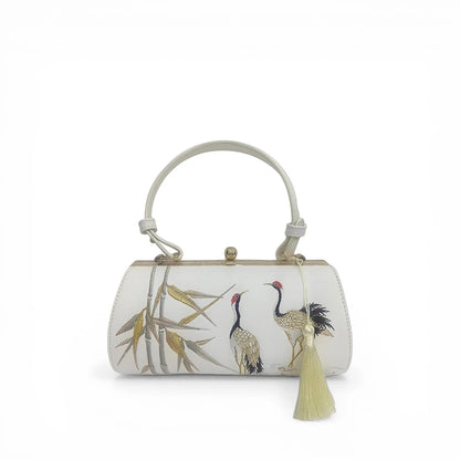 front view of white pu leather clutch bag with chinese crane and bamboo embroidery, tassel detail and top handle