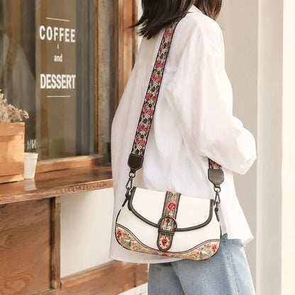 White floral embroidered saddle crossbody bag paired with white shirt and jeans, modeled outside retro coffee shop for casual street fashion look.